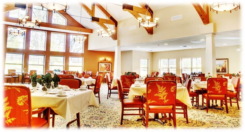 A cozy and elegant dining room with wooden beams, chandeliers, and neatly arranged tables and chairs.