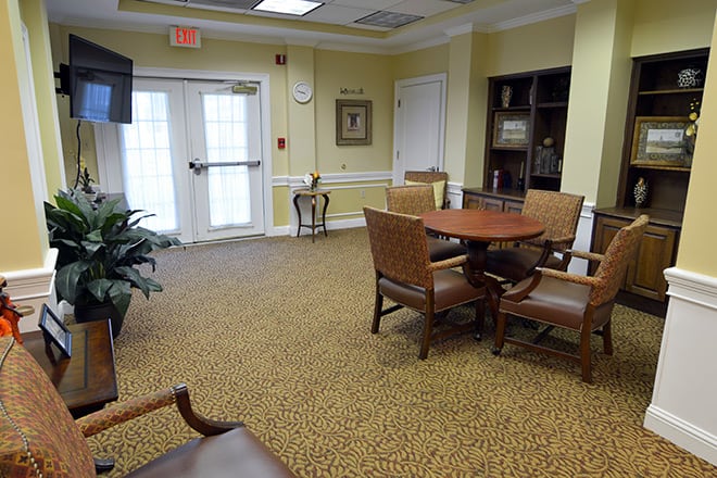 A comfortable waiting area with seating and a table, featuring decorative elements like a plant and bookshelf.