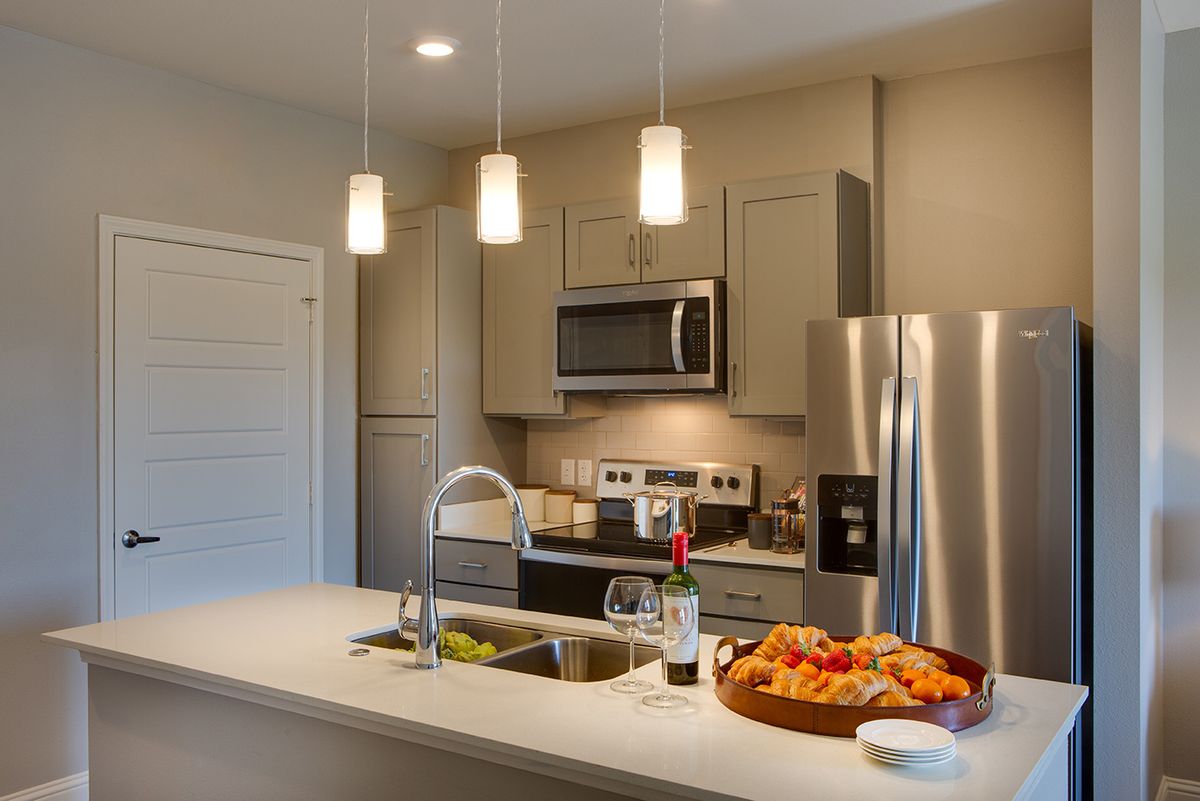 A modern kitchen featuring stainless steel appliances, a sleek countertop, and stylish lighting.