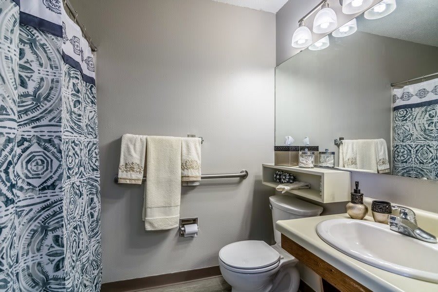 A modern bathroom with a toilet, sink, and shower area featuring a patterned curtain.