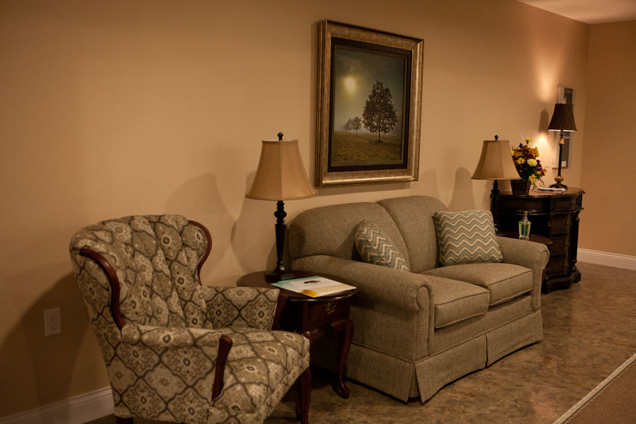 A cozy living room with a sofa, armchair, and decorative lamps.