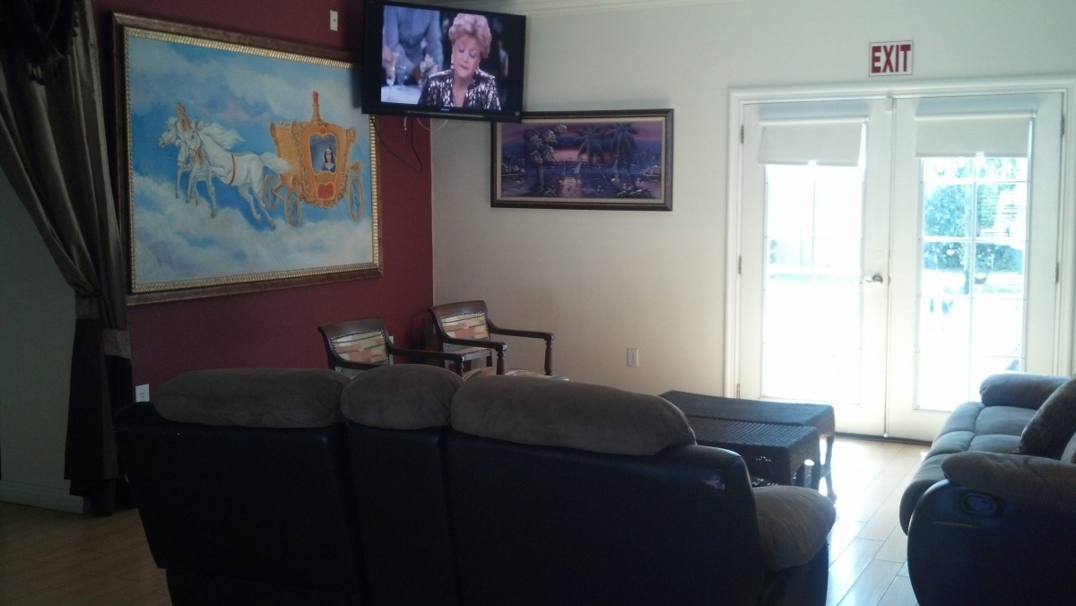 A cozy living room with a couch, artwork on the walls, and a television mounted above.