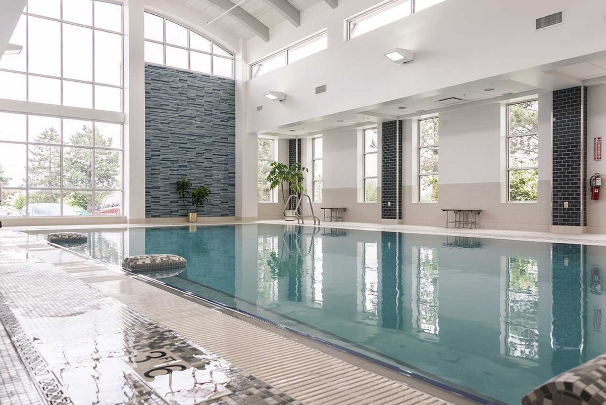 A modern indoor swimming pool with large windows and ample natural light.