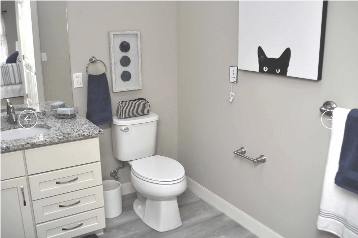 A modern bathroom with a playful cat-themed mirror decoration.