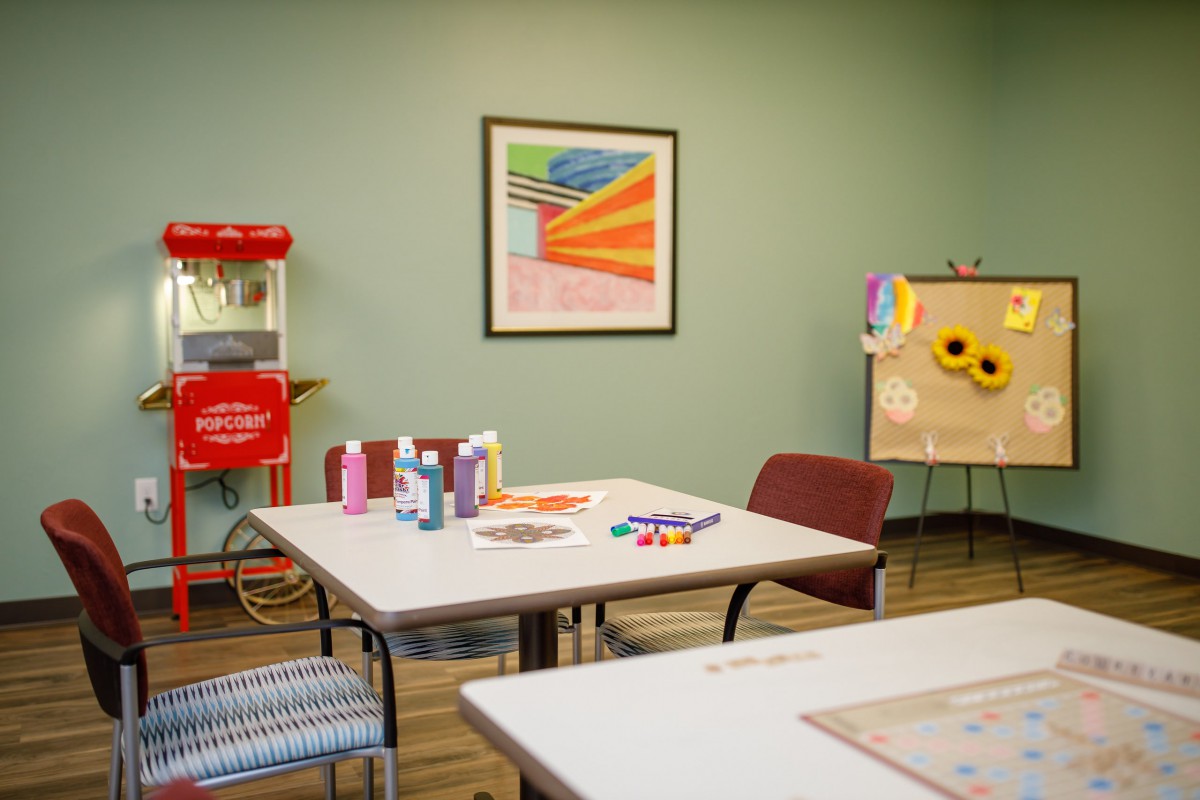 A well-equipped classroom with art supplies on tables and a popcorn machine in the corner.