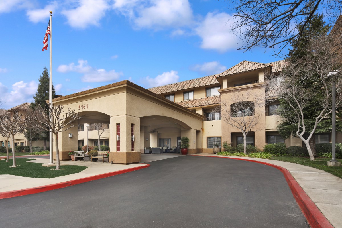 A modern hotel entrance with a covered driveway and clear blue sky.