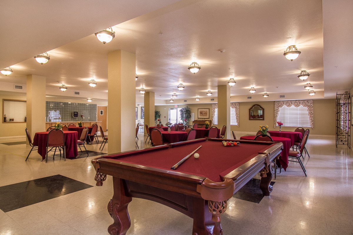 A well-lit recreation room featuring a billiards table and seating area.