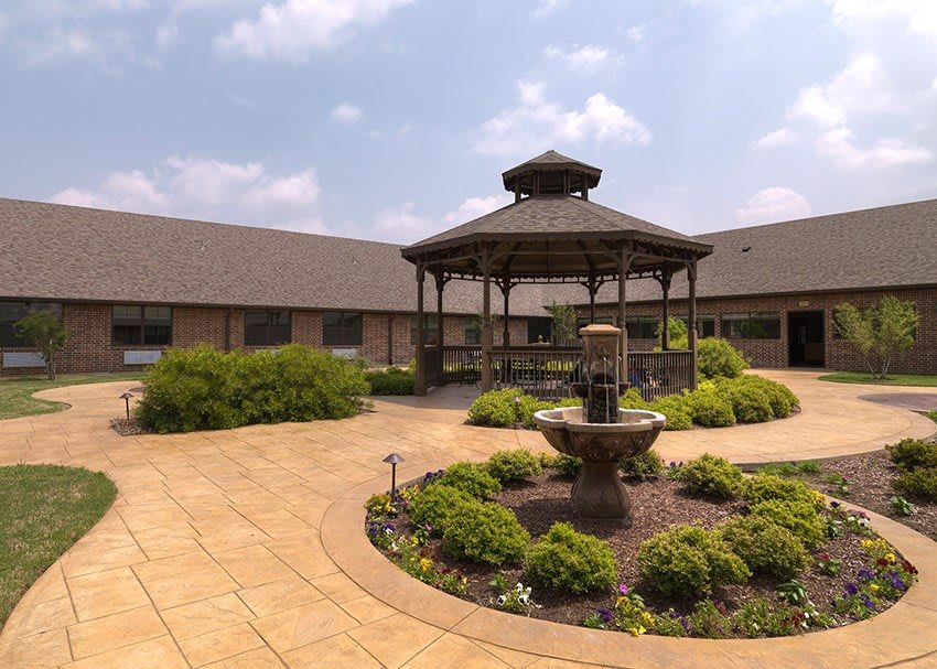 A courtyard featuring a gazebo and fountain surrounded by lush greenery.