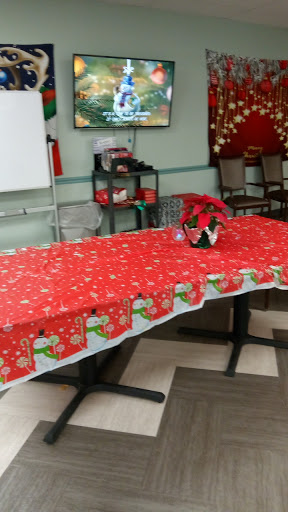 A festive setup for a holiday gathering, featuring a red tablecloth adorned with Christmas-themed designs and a poinsettia plant as a centerpiece.