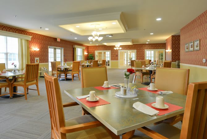 A neatly arranged dining room with elegantly set tables and comfortable chairs.