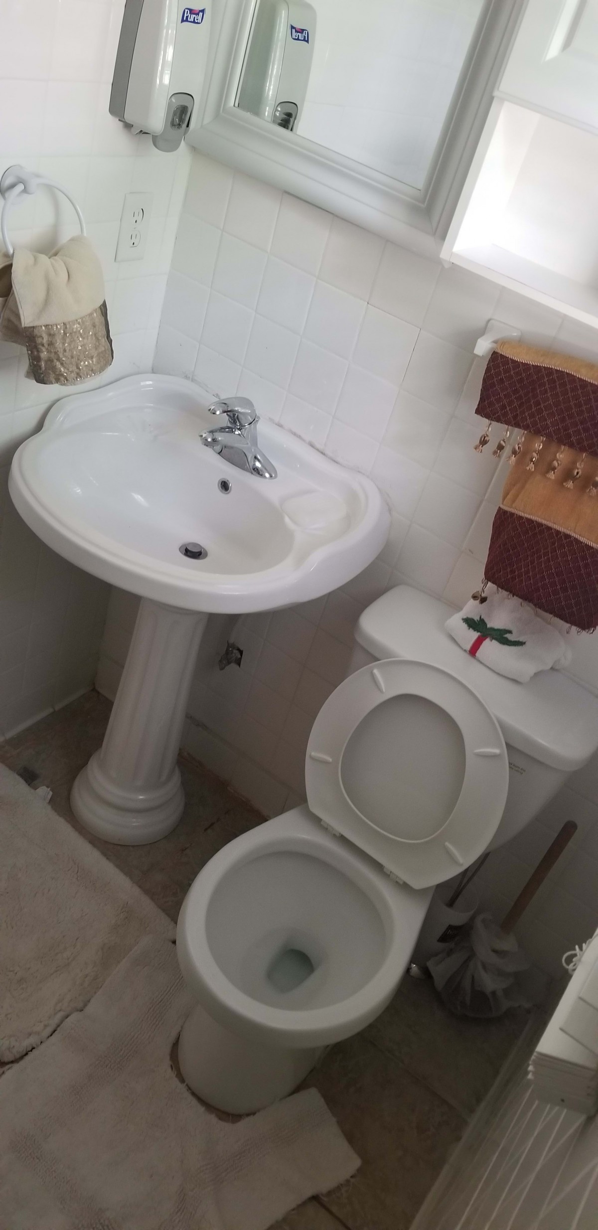 Compact bathroom with a sink and toilet alongside a towel rack.