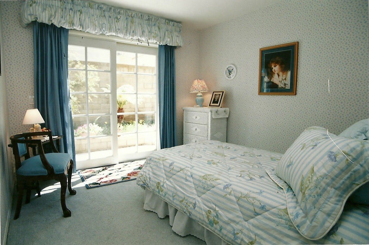 A cozy bedroom with a bed, lamp, and sliding glass door.