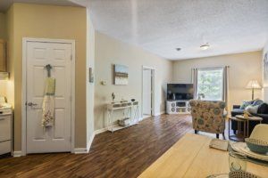 A cozy living room with hardwood flooring, featuring a television and comfortable seating.