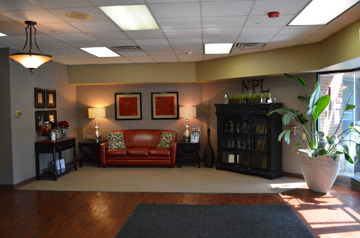A cozy lobby area featuring a red couch, decorative lamps, and a bookshelf.