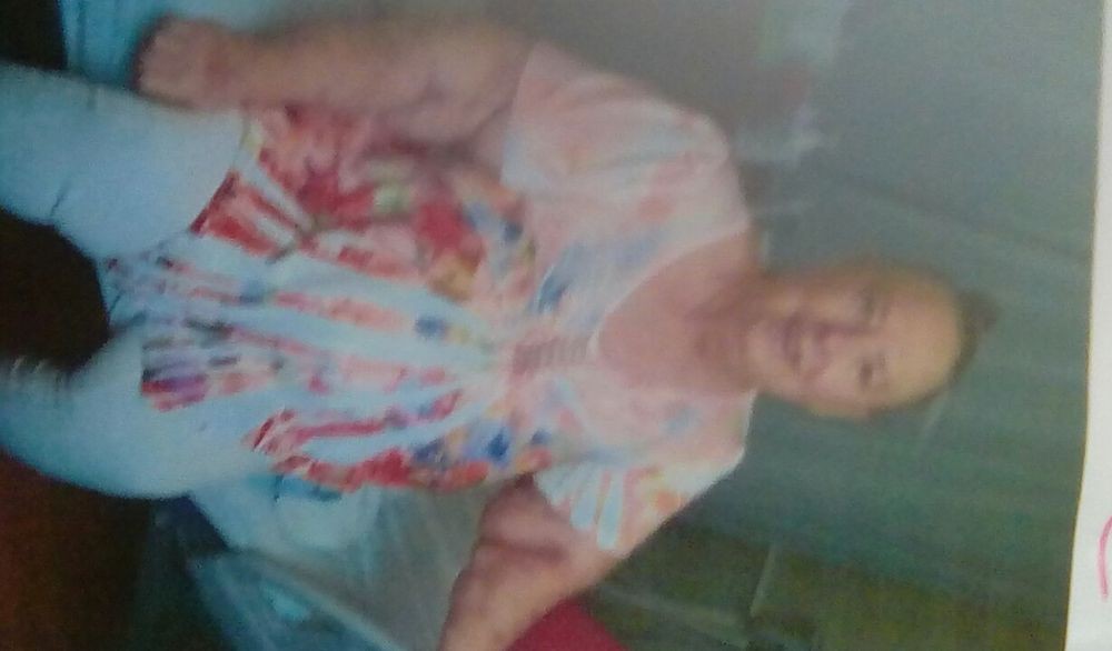 A blurry photo of a woman standing indoors, wearing casual clothing.