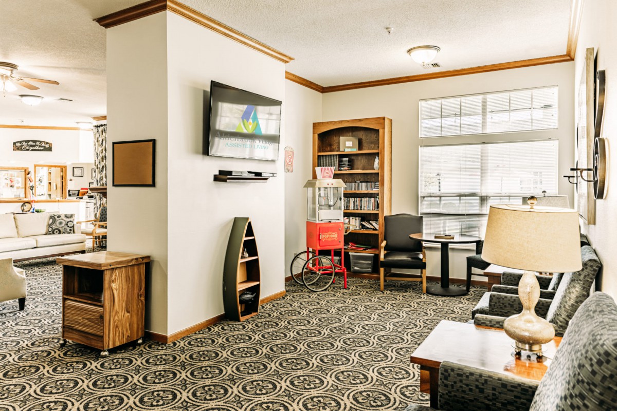A cozy living room with a television, bookshelf, and seating area.