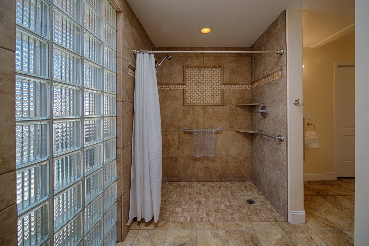 A modern bathroom with a spacious walk-in shower featuring glass blocks and a curtain.