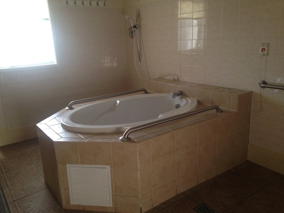 A tiled bathroom featuring a whirlpool bathtub set in an elevated platform.