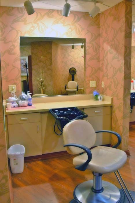 A hair salon station with a chair, mirror, and various styling tools on the counter.
