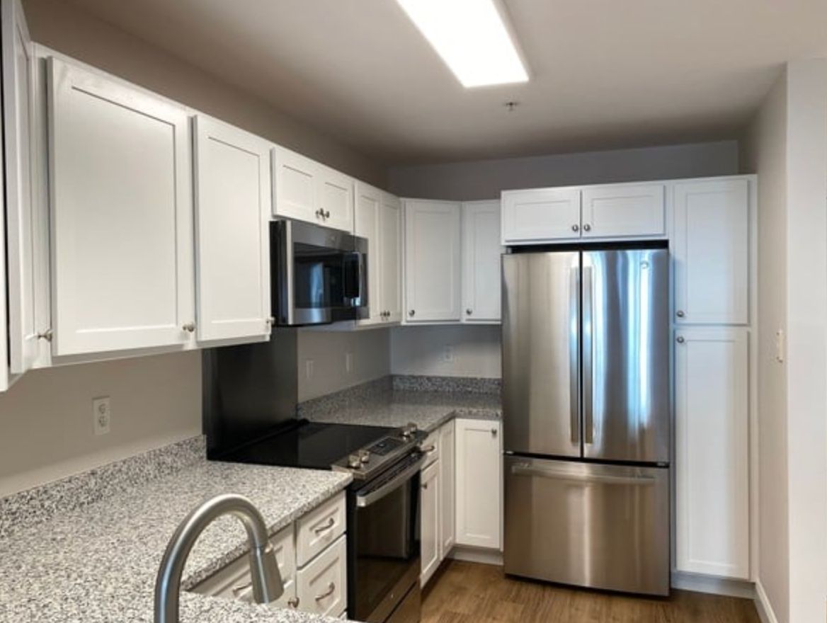 A modern kitchen with white cabinets and stainless steel appliances.