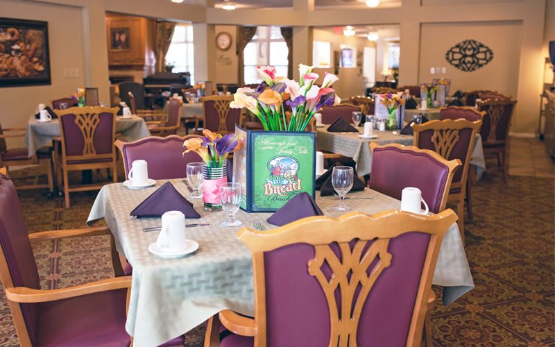 An elegantly set dining area with decorated tables and comfortable chairs.