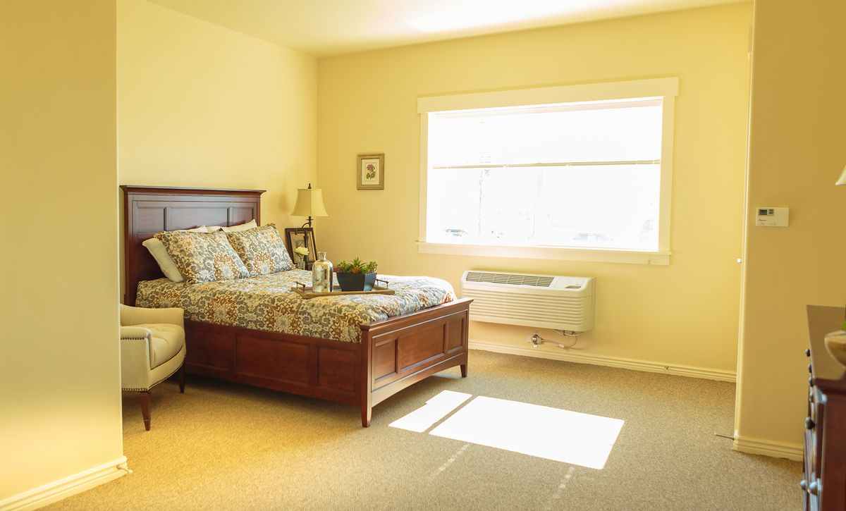 A cozy bedroom with a wooden bed frame, daylight streaming through the window.