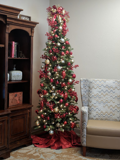 A beautifully decorated Christmas tree with red and gold ornaments, set in a cozy living room.
