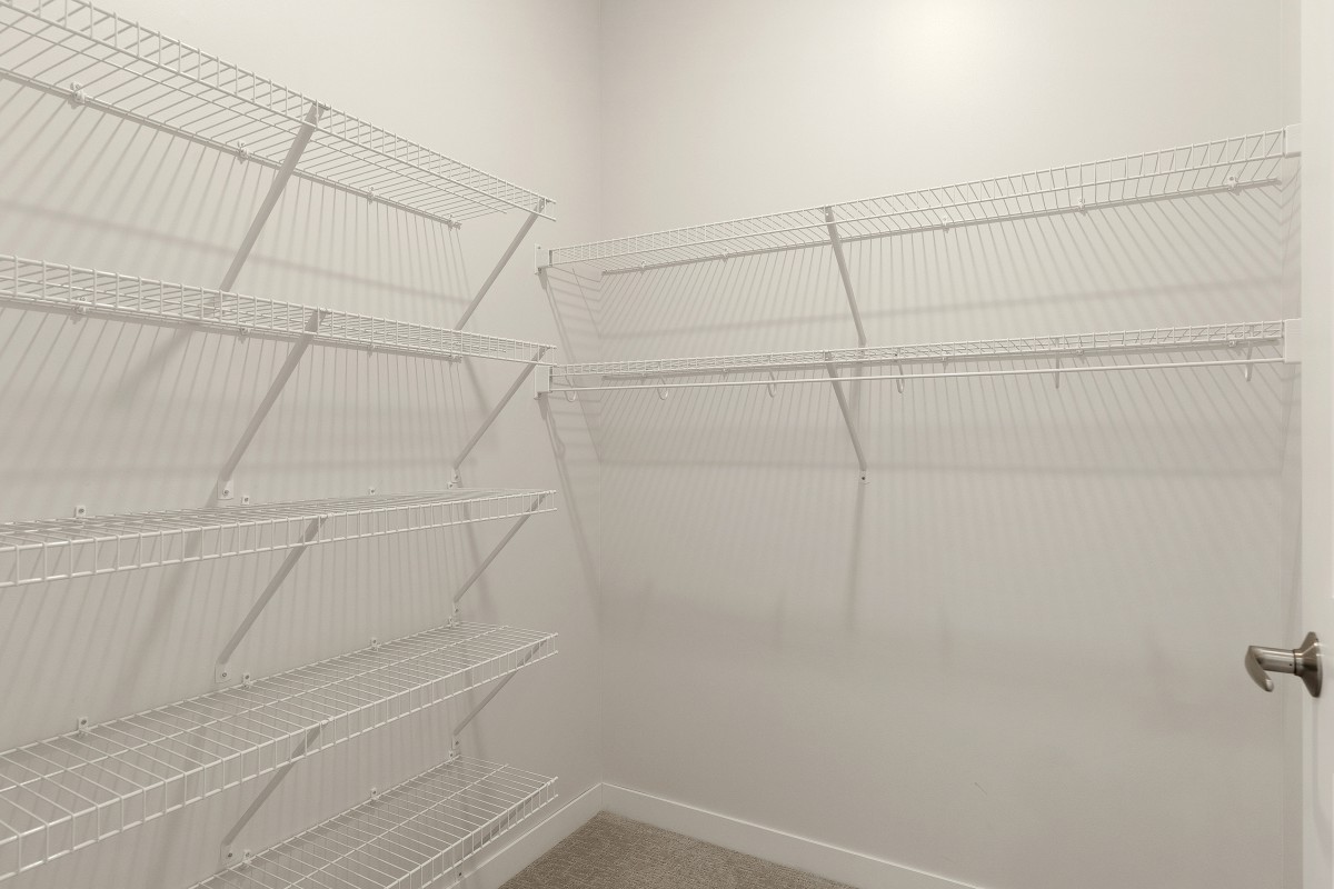 An empty closet with white wire shelving and white walls.