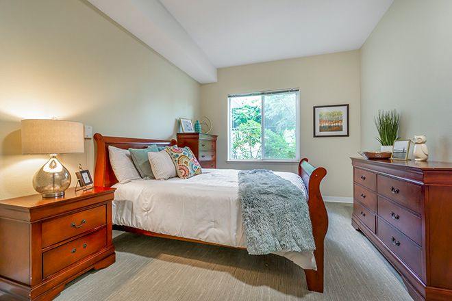 A cozy bedroom with wooden furniture and a large window.