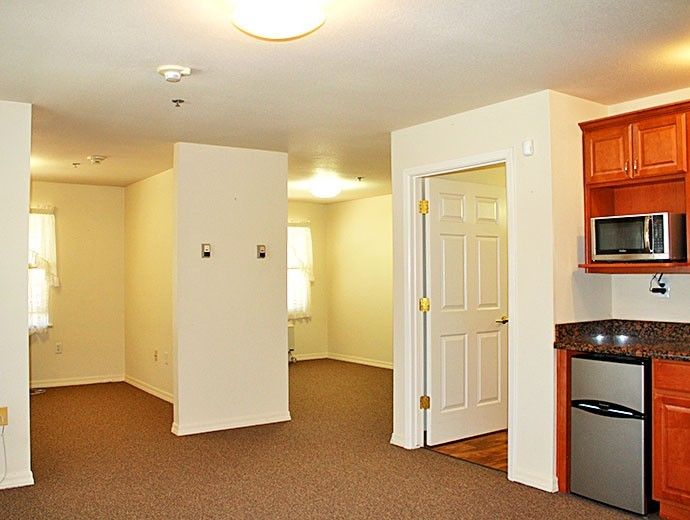 An empty apartment with a small kitchen and open living space.