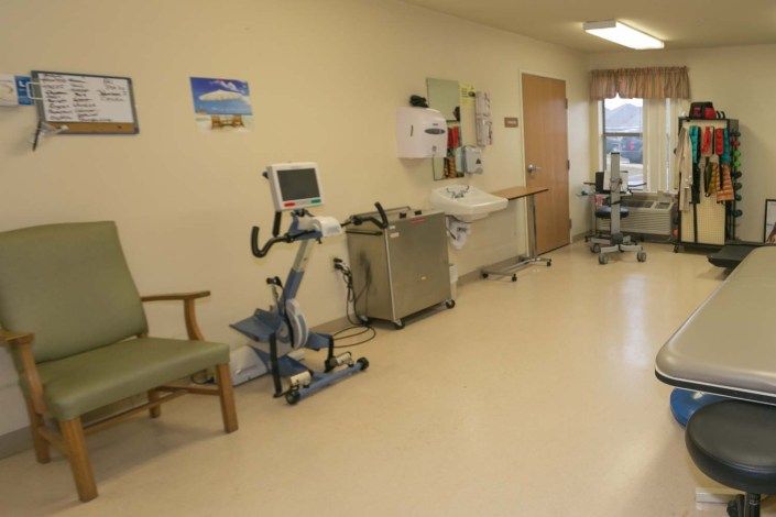 A hospital rehabilitation room featuring an exercise bike and various medical equipment.