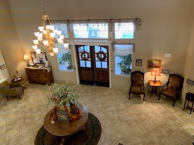A spacious and elegantly decorated foyer with a chandelier, wooden doors, and stylish furniture.