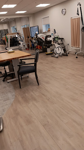 A spacious rehabilitation office featuring wooden floors and exercise equipment.