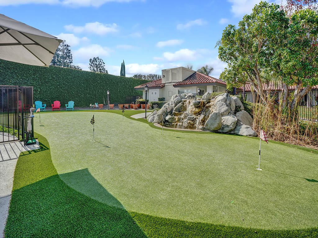 A beautifully landscaped residential putting green with artificial turf.