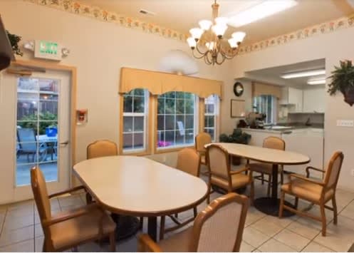 A cozy dining area with tables, chairs, and a view into the kitchen.