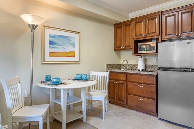 A cozy kitchenette with wooden cabinets, a small dining table, and modern appliances.