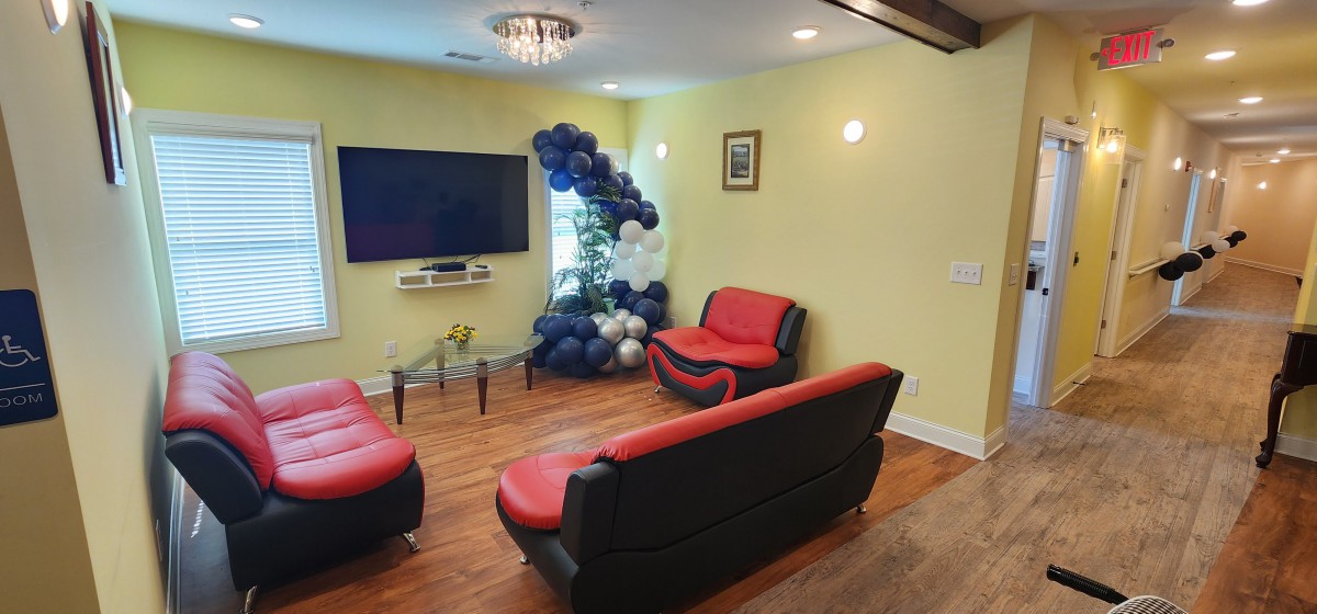 A modern living room with a television, red and black sofas, and a balloon decoration near the window.