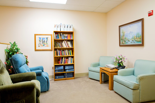 A cozy waiting room featuring comfortable seating and a bookshelf filled with various reading materials.