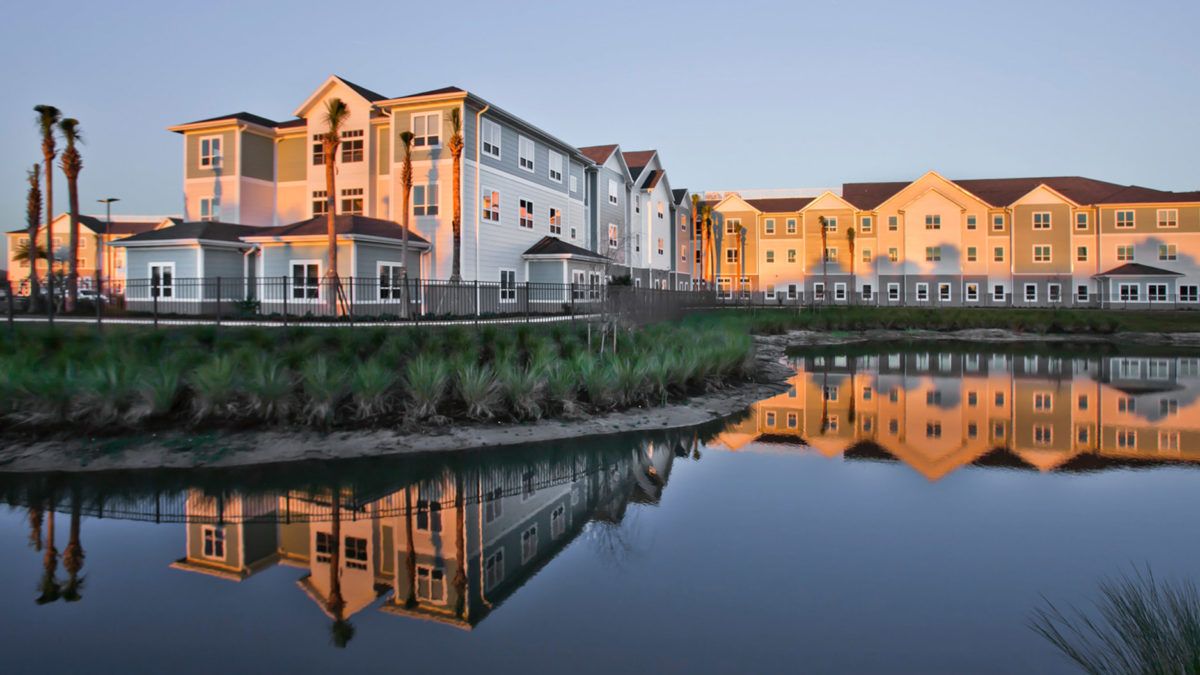 A picturesque view of buildings reflecting on a calm lake at sunset.