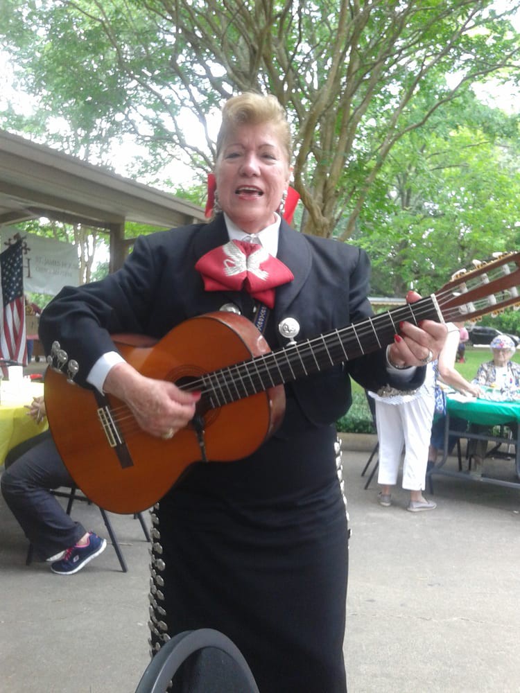Mariachi musician performing outdoors with a guitar.
