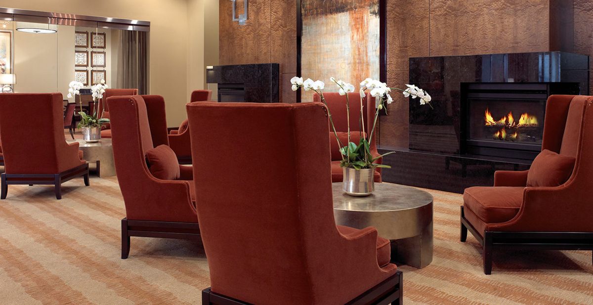A modern lounge area with vibrant red chairs and a central silver table adorned with orchids.