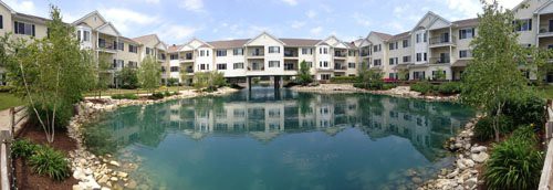 A residential apartment building reflected in a calm lake.