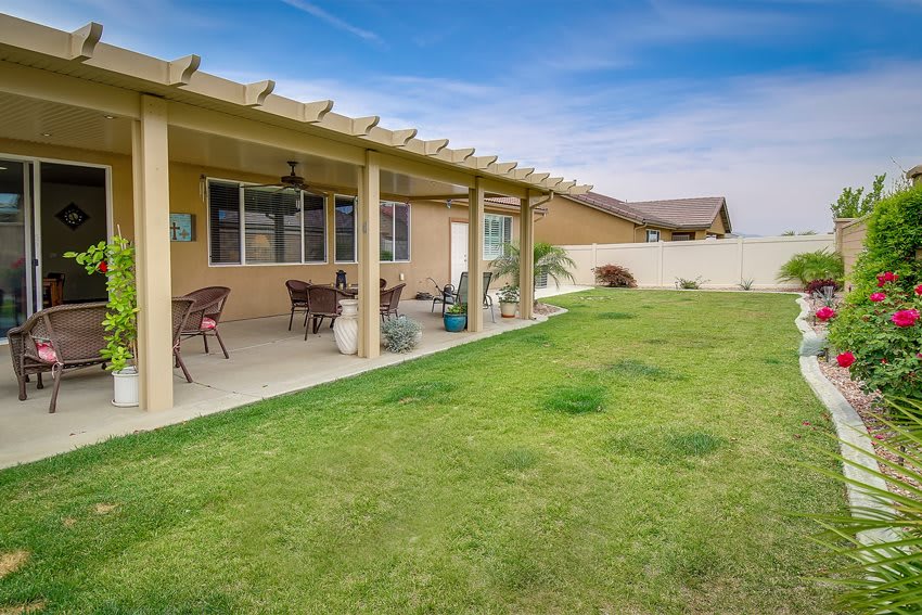 A spacious backyard with a covered patio and well-maintained lawn.