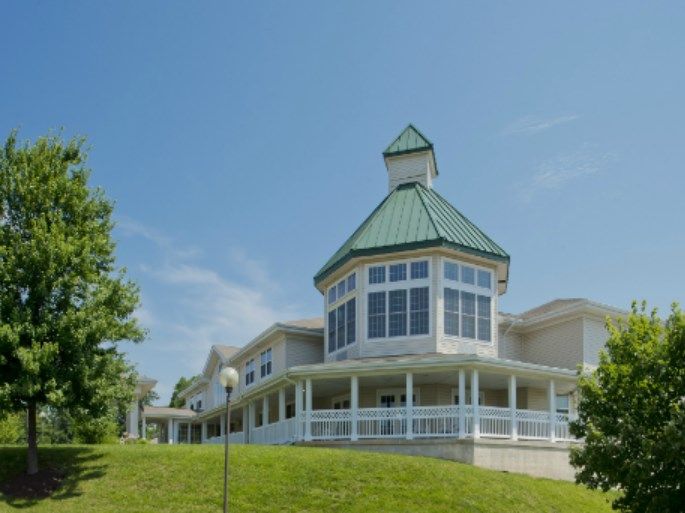A large building with a distinctive green rooftop and wraparound windows set against a clear blue sky.