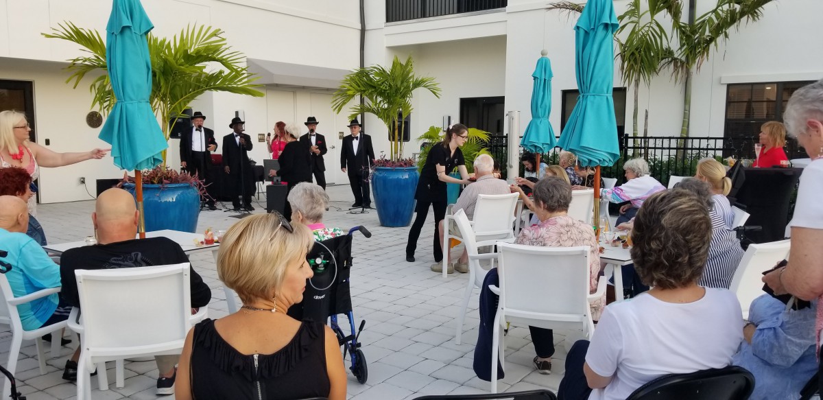 An outdoor gathering where people are seated and performers are entertaining the audience.