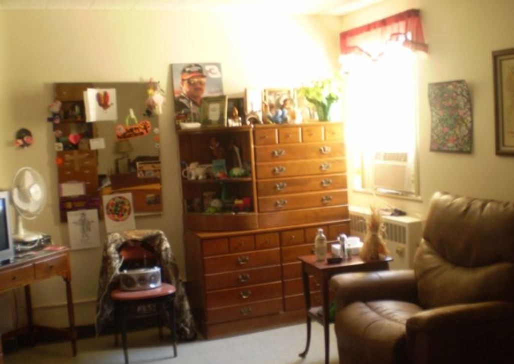 A cozy living room with a dresser, bookshelf, and comfortable seating arrangement.