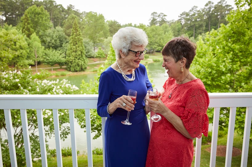 Two women enjoying a toast together on a scenic outdoor balcony.
