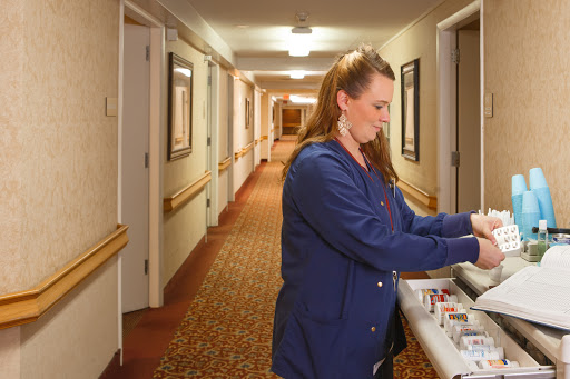 A healthcare worker preparing supplies in a hotel hallway.