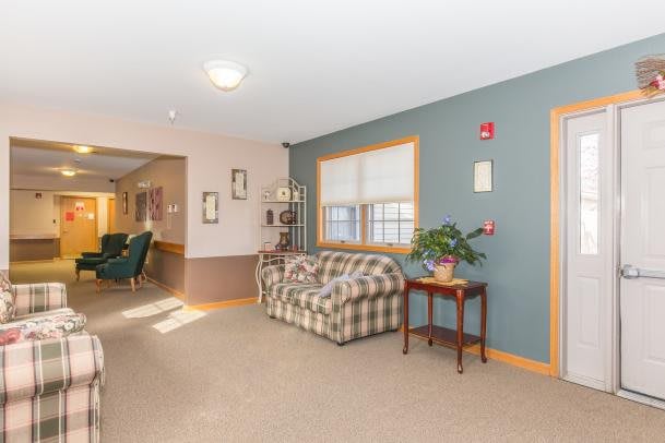 A cozy lobby area featuring a plaid couch and a small table with a plant beside it.