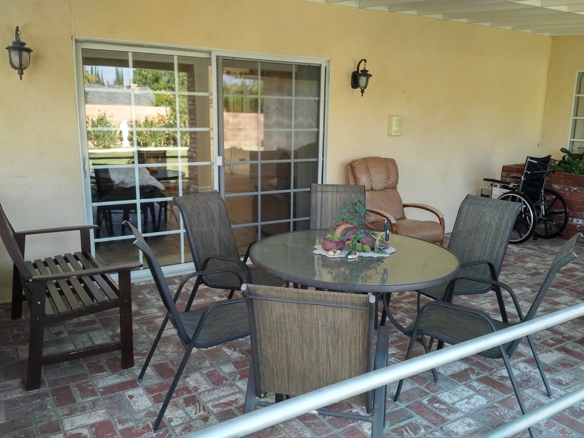 A cozy outdoor patio area with a round table, several chairs, and brick flooring.